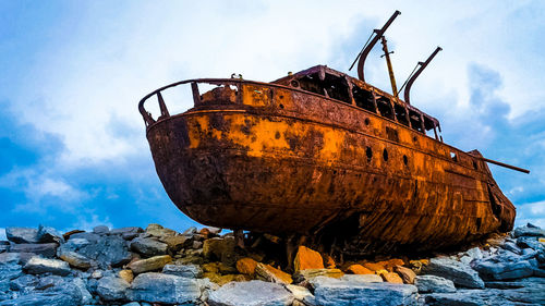 Shipwreck on rocks at beach against sky