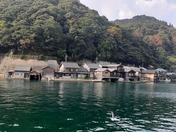 Houses by lake and buildings against mountain