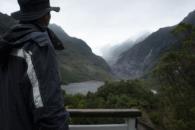 Rear view of man standing on mountain against sky