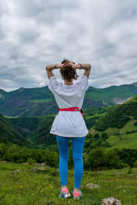 Rear view of woman standing on mountain against sky