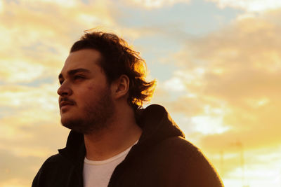 Close-up of young man against sky during sunset