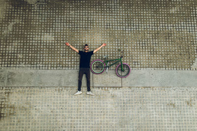 Full length of man with bicycle lying on footpath