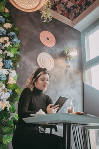 Young woman sitting on table at home