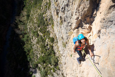 Young woman climbing through a via ferrata in chulilla canyon (spain)