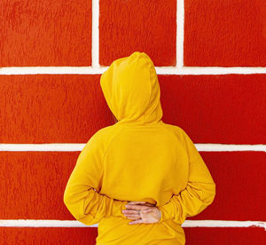 Rear view of woman standing against red wall