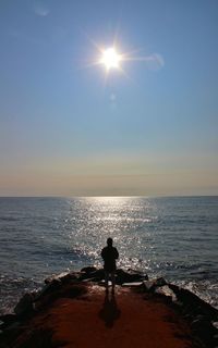 Silhouette woman standing on sea against sky