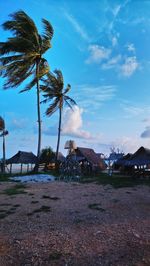 Scenic view of palm trees and houses against sky