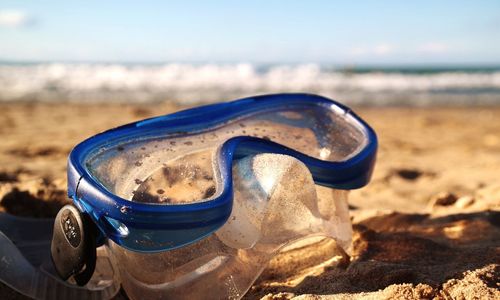 Close-up of scuba mask on sand at beach