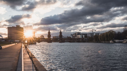 Oberbaum bridge over river against cloudy sky during sunset