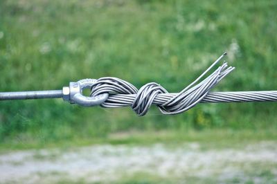 Close-up of barbed wire fence on field