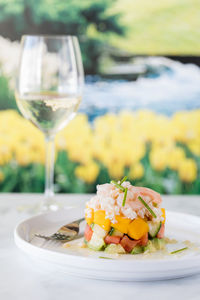 A crab and shrimp stacked salad served with a glass of white wine in soft focus.