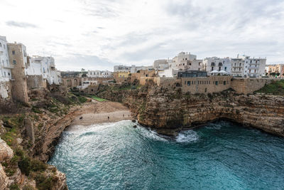 Buildings by sea against sky