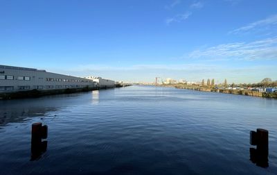 Bridge over river by buildings against blue sky