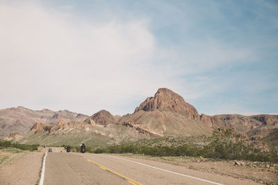 Bikers riding motorcycle on route 66 against sky