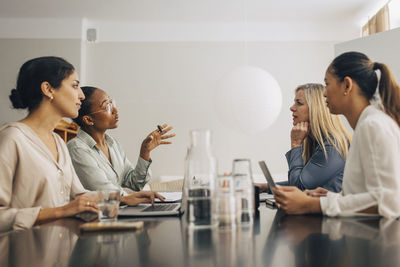 Multiracial female creative professionals discussing with each other during business meeting in office