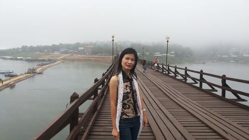 Portrait of woman standing on bridge over river
