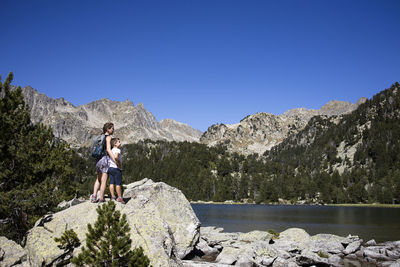 Full length of man standing on rocks against clear blue sky