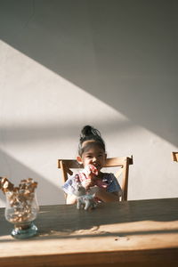 Boy sitting on table against wall