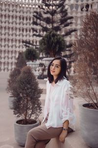 Portrait of young woman standing against wall