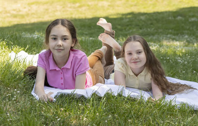 Portrait of siblings sitting on grassy field