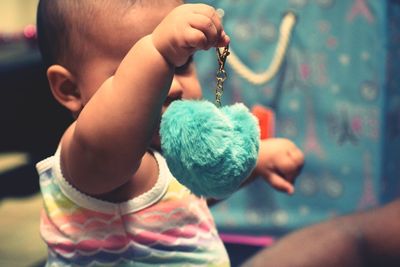 Close-up of baby girl holding keychain at home