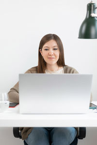 Portrait of smiling young woman using laptop at home