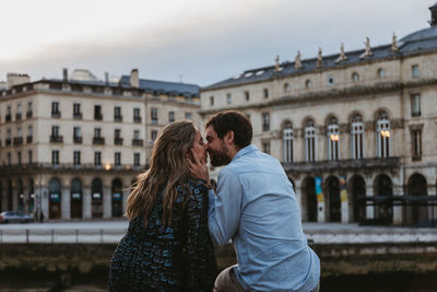 Couple kissing against buildings in city