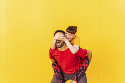 Couple holding yellow while standing against wall