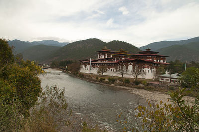 Scenic view of river by buildings against sky