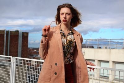Portrait of beautiful young woman wearing overcoat in city