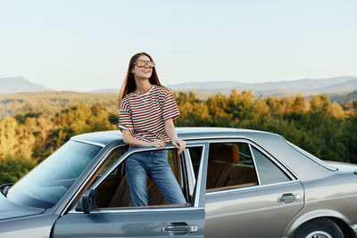 Side view of young woman holding car