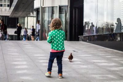 Rear view of boy walking on street in city