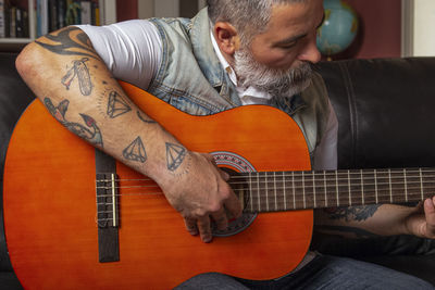 Midsection of man playing guitar