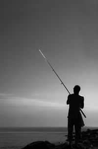 Rear view of man standing on sea against clear sky