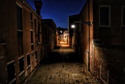 Narrow alley along buildings at night