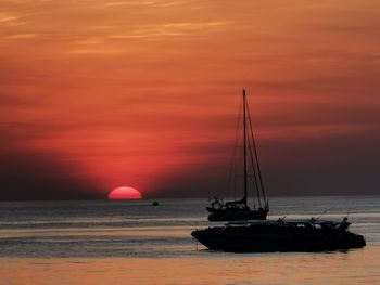 Sailboat on sea against orange sky