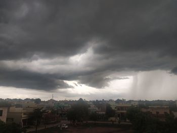 Buildings in city against storm clouds