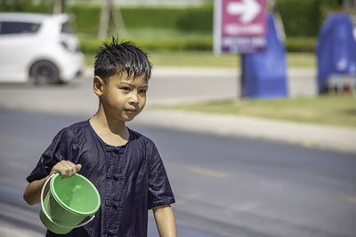 Portrait of boy standing on road in city