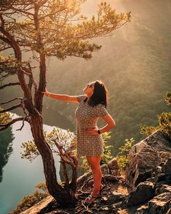 Woman standing by tree against plants