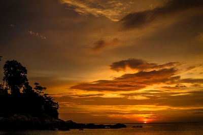 Scenic view of sea against dramatic sky during sunset