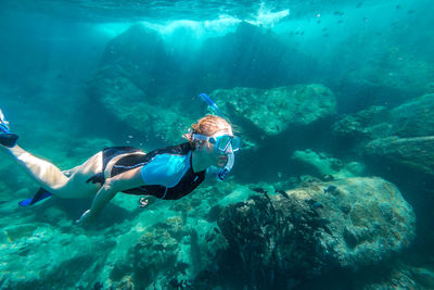 Woman snorkeling over rocks undersea