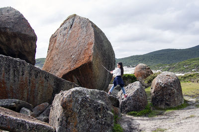 People on rock by mountain against sky