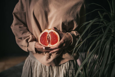 Midsection of woman holding strawberry