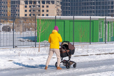 Full length rear view of woman standing in snow