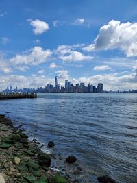 Sea by buildings in city against sky