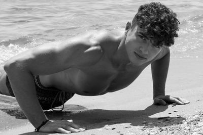 Portrait of shirtless man doing push-ups at beach
