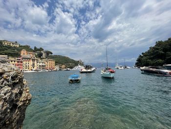 Sailboats moored in sea against sky