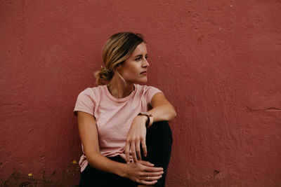 Woman looking away against wall