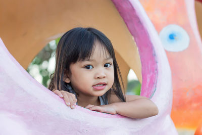 Portrait of cute girl through play equipment at park