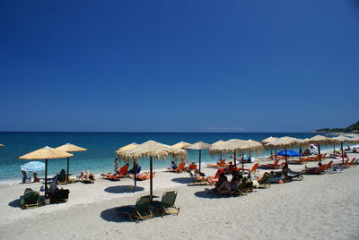 Panoramic view of people on beach against clear blue sky